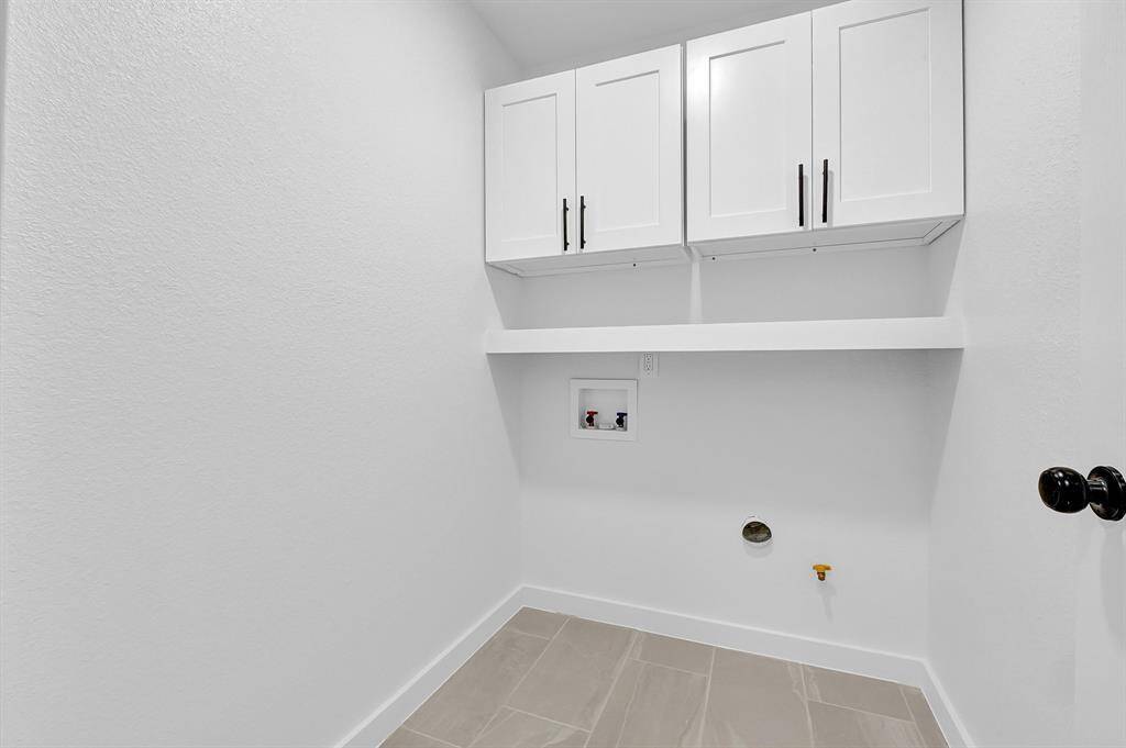 This bright room features sleek tile flooring, a modern ceiling fan, and a large window with blinds. It includes a small closet with a white door, offering a clean and inviting space.