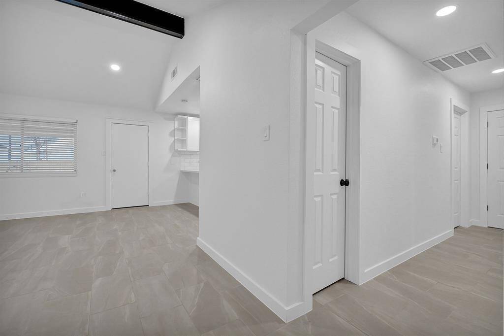This photo shows a bright, compact laundry room with white cabinetry, tile flooring, and hookups for a washer and dryer.