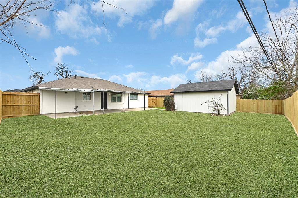 This photo features a single-story brick home with a modern black garage door and a covered driveway. The exterior is well-maintained, with a neatly manicured lawn and a clear blue sky overhead, creating a welcoming curb appeal.