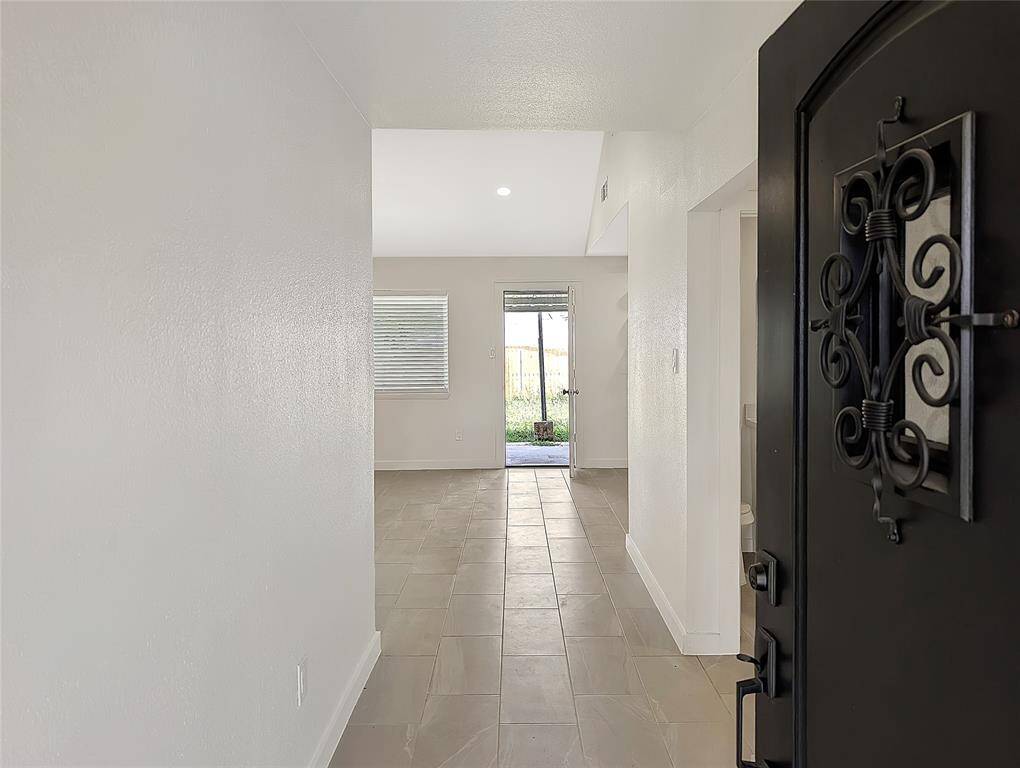 This bathroom features a sleek, modern design with a white vanity and black fixtures. The shower area is adorned with large, marble-patterned tiles, complemented by a glass partition. The space is well-lit and offers a clean, contemporary aesthetic.