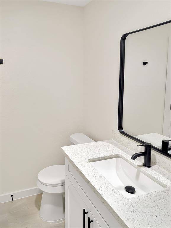 This room features a clean, modern look with white walls and recessed lighting. It has light wood-style flooring, a window with blinds, and a vaulted ceiling with an exposed beam, creating a bright and spacious atmosphere.