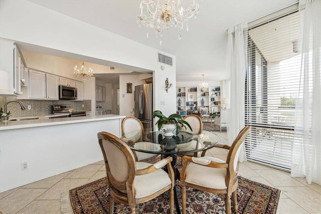 Open flow living and dining areas, custom shelving, a designer chandelier, and direct balcony access.