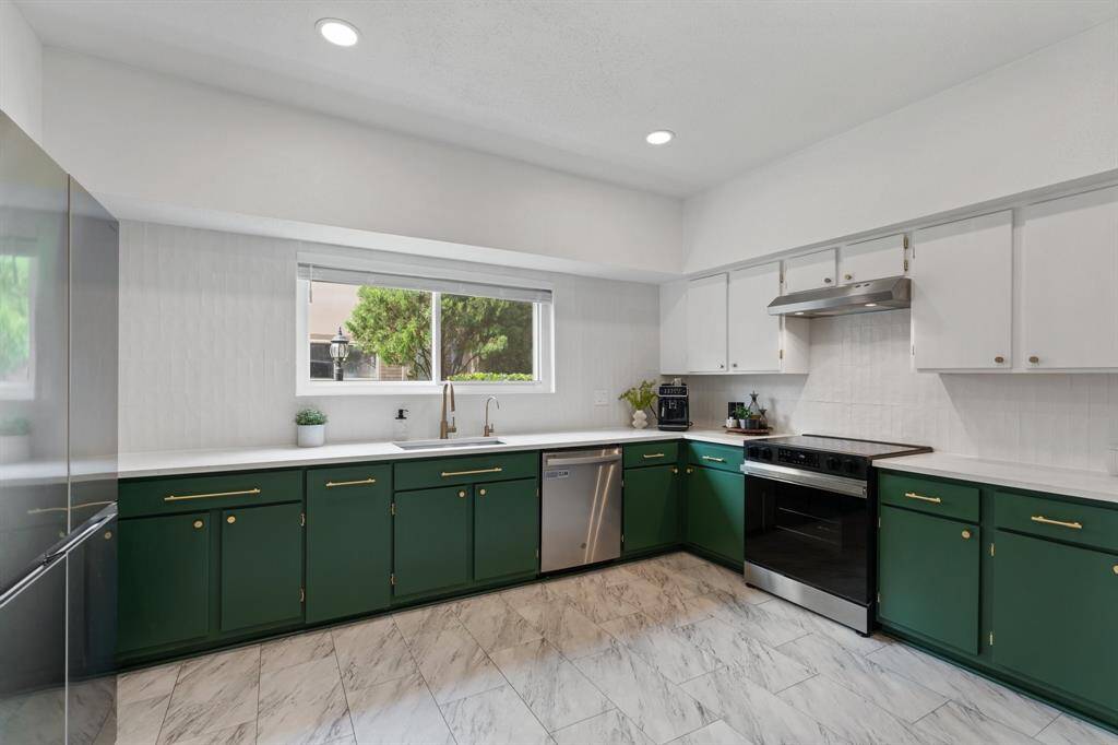 The dining room features a modern chandelier and large windows with ample natural light. It includes a built-in bar area with shelving for bottles, creating a sophisticated and inviting atmosphere.