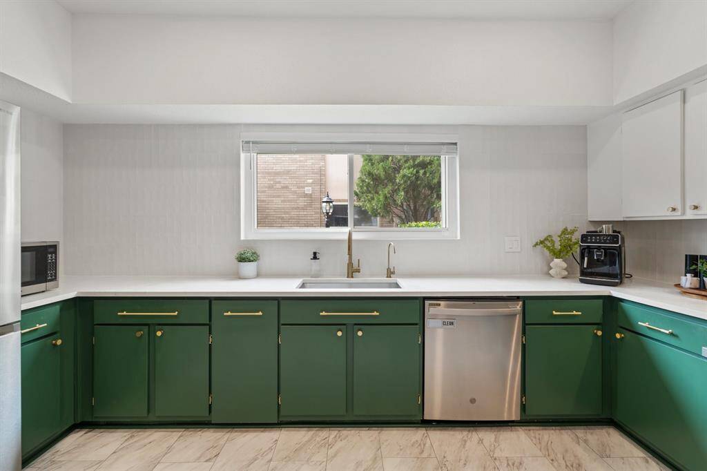 This photo showcases a dining area with a built-in bar alcove. The bar features a mirrored back, glass shelves, and green lower cabinets, adding a touch of elegance. Adjacent is a hallway leading to the kitchen with visible cabinetry, suggesting ample storage and a seamless flow between spaces.