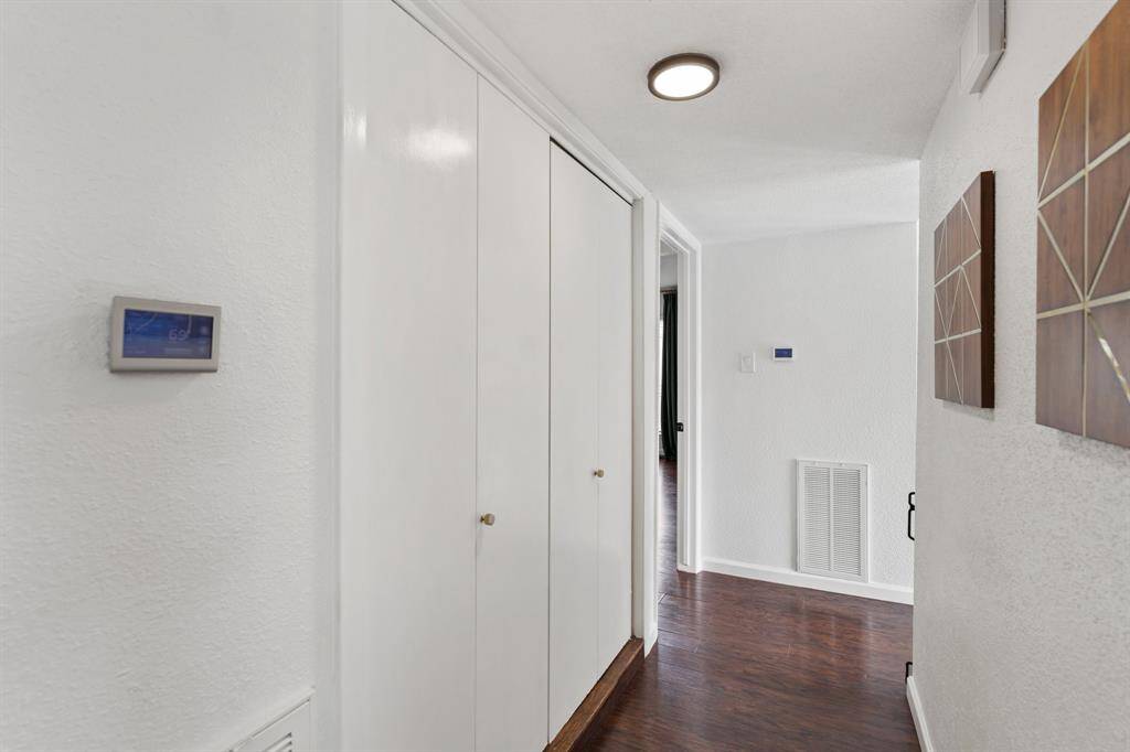 This primary bathroom features a modern design with dark green tiled shower walls, a glass door, and a sleek, white toilet. The lighting is bright, and the fixtures have a contemporary finish.