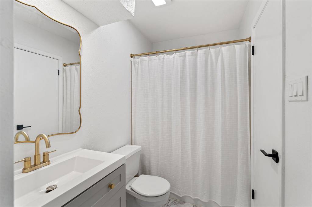 The secondary bedroom is a bright, modern bedroom featuring white walls and a ceiling fan. The room is well-lit with natural light from a large window. It features a walk-in closet and direct access to the secondary bathroom.