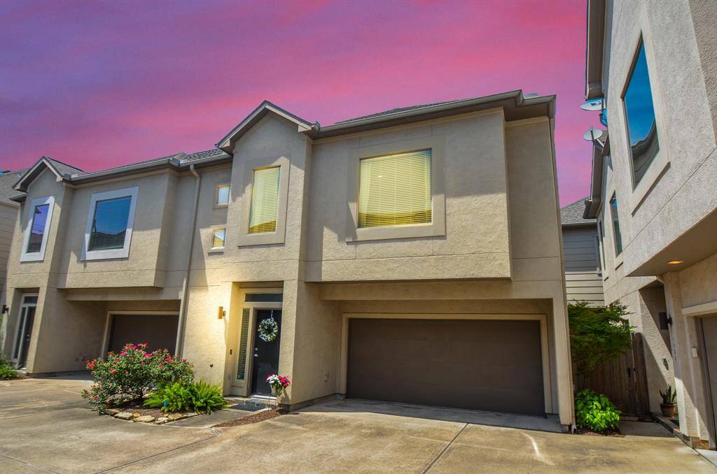 Modern townhouse features a two-story design with a clean stucco exterior, a double garage, and well-maintained landscaping. It’s situated in a neat row of similar homes, offering a welcoming community feel.