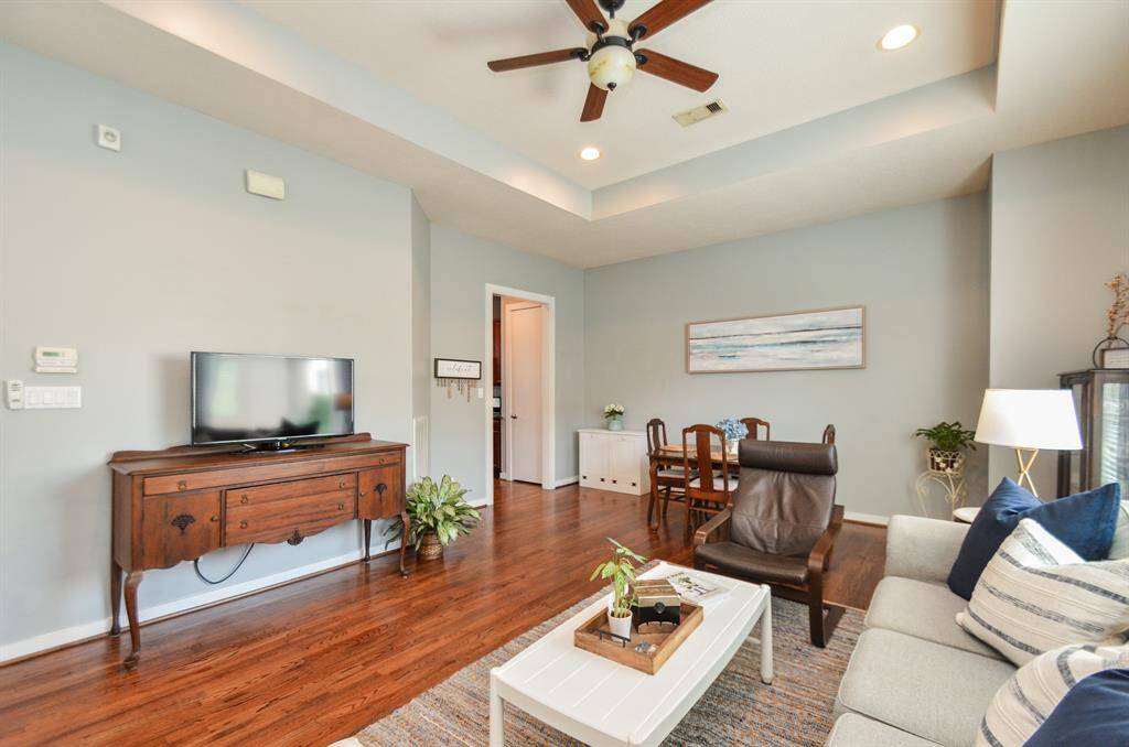 Inviting living space features an open layout with hardwood floors, a cozy seating area, and a dining table. Large windows provide ample natural light, Recessed lighting and a ceiling fan add a modern touch, well-suited for relaxation and entertaining.