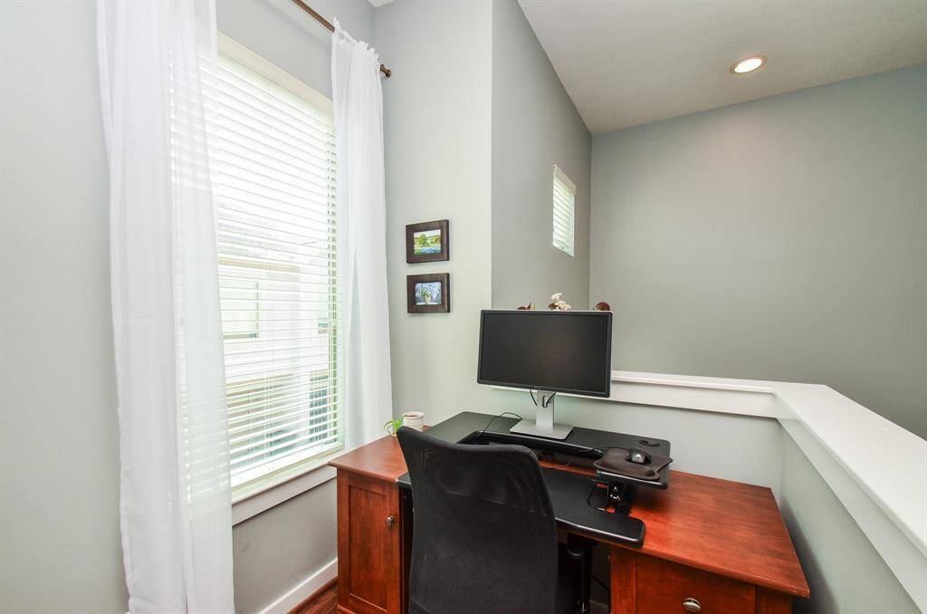 Cozy living and dining area with hardwood floors, soft gray walls, and a large window providing natural light. Features a comfy sofa, modern decor, and a dining set, creating an inviting space for relaxation and entertaining.