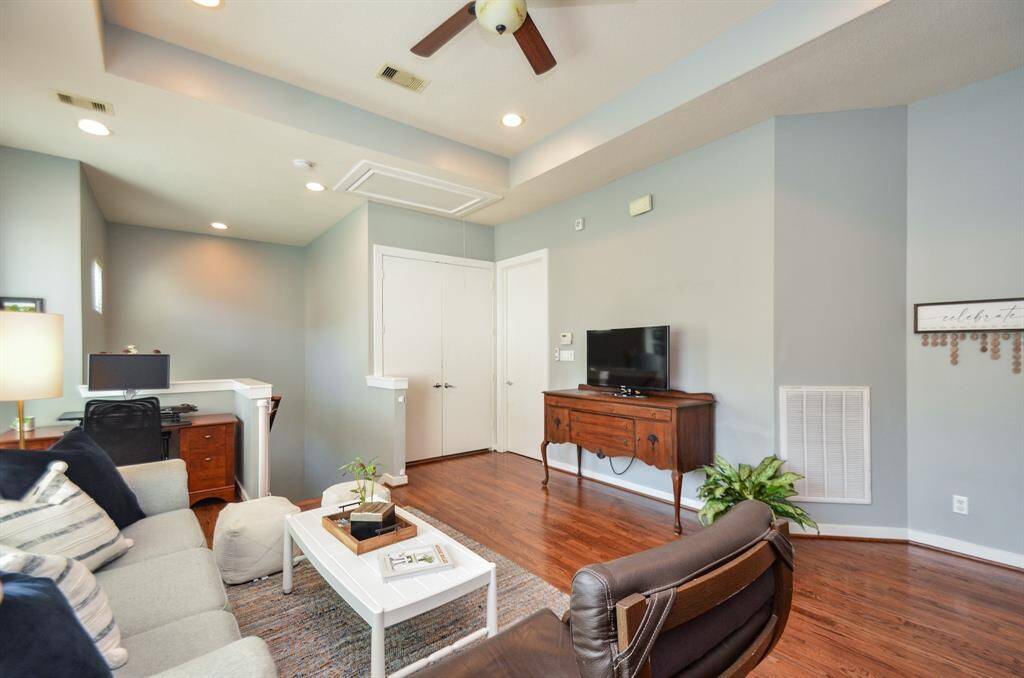 Home office nook with natural light, featuring a wooden desk, computer setup, and soft gray walls. Ideal for focused work or study.