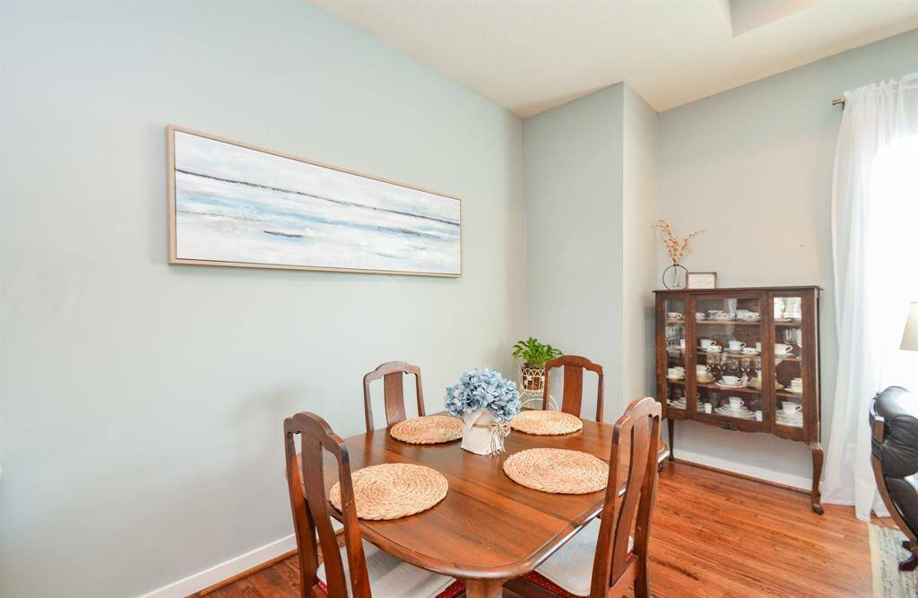 Dining area hardwood flooring, leading into a kitchen with wood cabinets, high ceilings, and modern appliances.