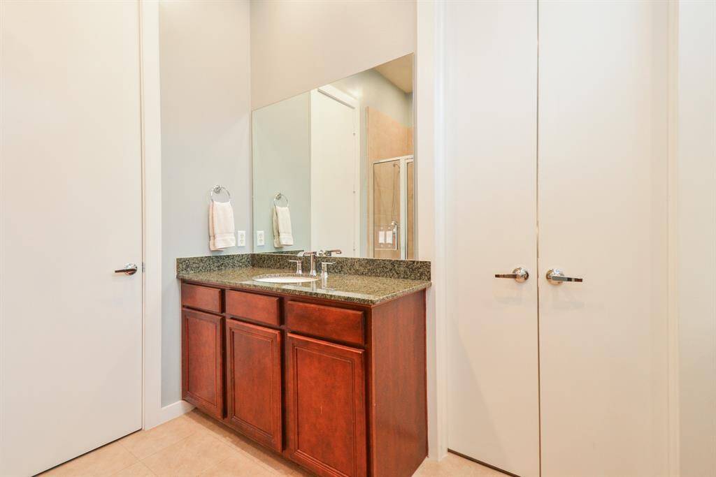 Primary bathroom features a 2nd sleek (His and Hers) vanity with a granite countertop and rich wood cabinetry for storage. Modern fixtures, 2024 upgraded faucets and neutral-toned tile flooring, creating a clean and stylish space.