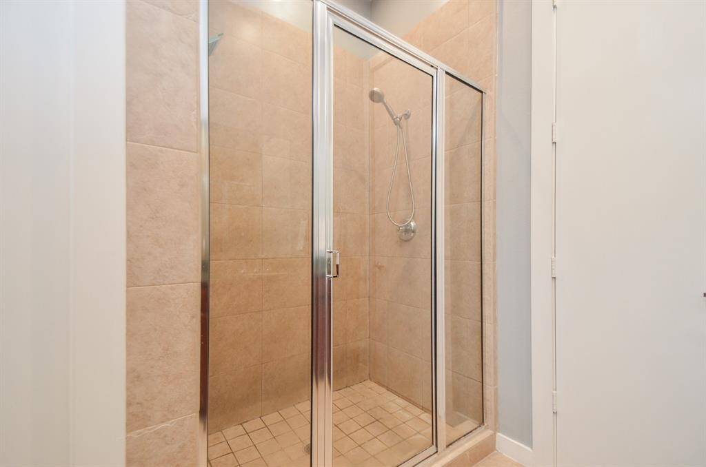 This is a clean, tiled walk-in shower with glass doors, featuring a modern shower head and rain shower head.