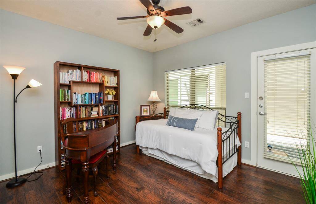 Charming Cozy patio area with a metal bench adorned with colorful cushions and a potted plant. A glass-panel door with blinds leads inside to 2nd bedroom or Home/office space.