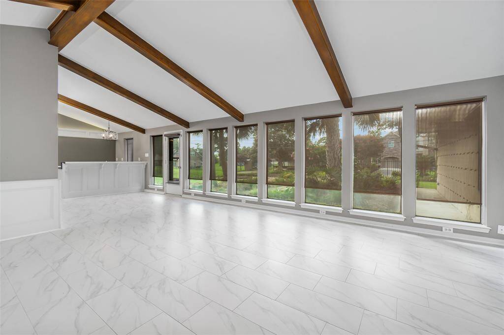 A wall of windows flanks the back of the house overlooking the landscaped yard.