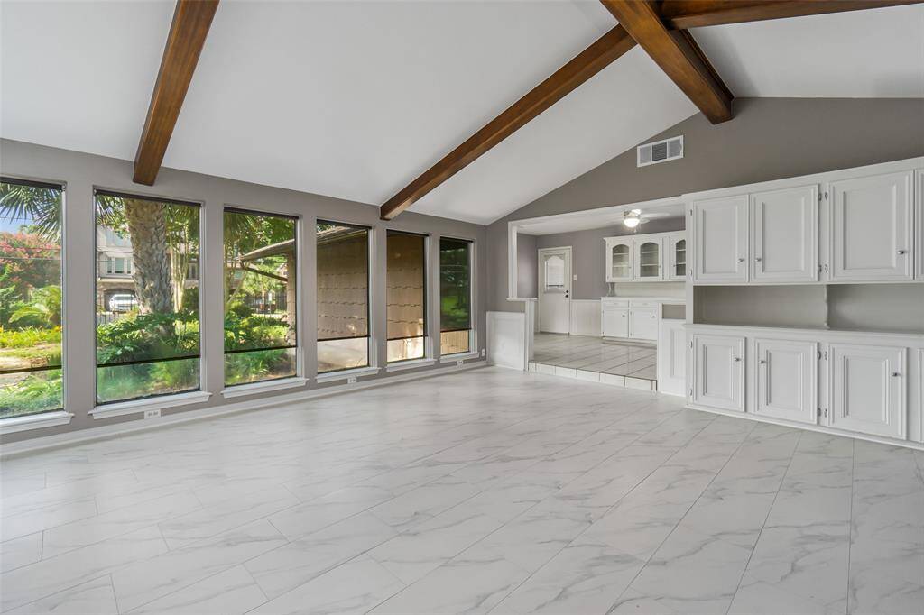 The sun room / family room brings in lots of light, but also has transparent "tinted" shades. Note the overhead beams, recent floors and built-in cabinets. This portion of the house was added on by a previous owner.