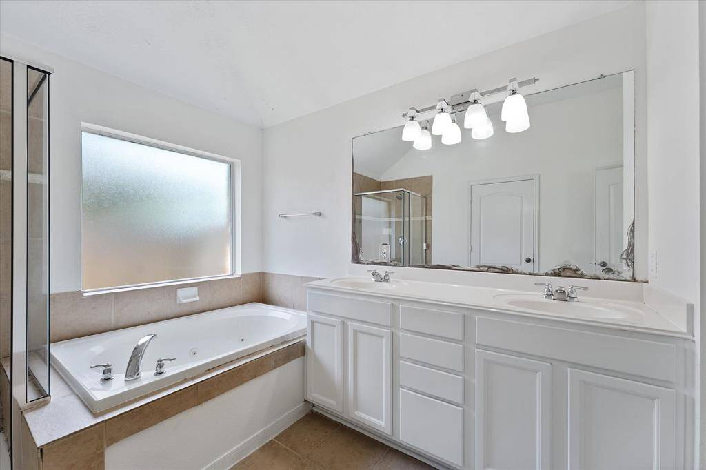 Dual vanities & jetted tub for relaxing in the primary bathroom.
