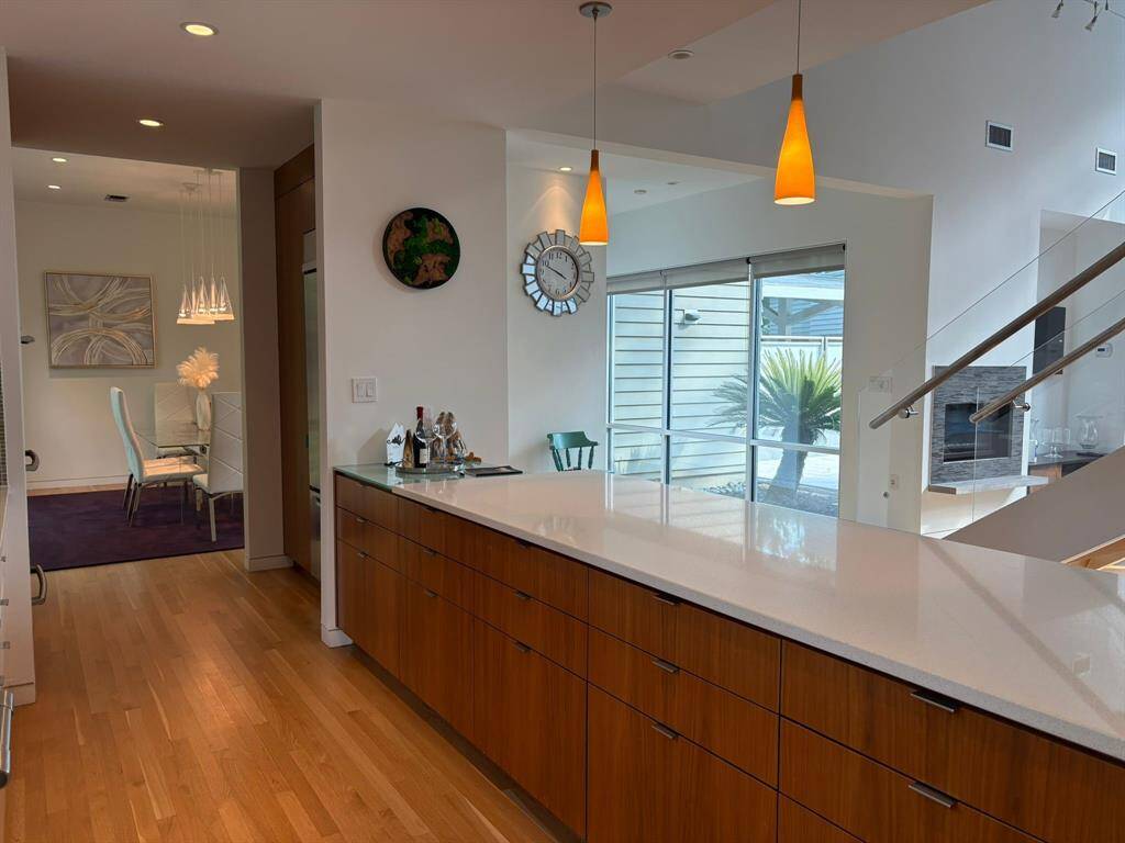 Streamlined white cabinetry and quartz counters blend with a mosaic tile backsplash and modern appliances.