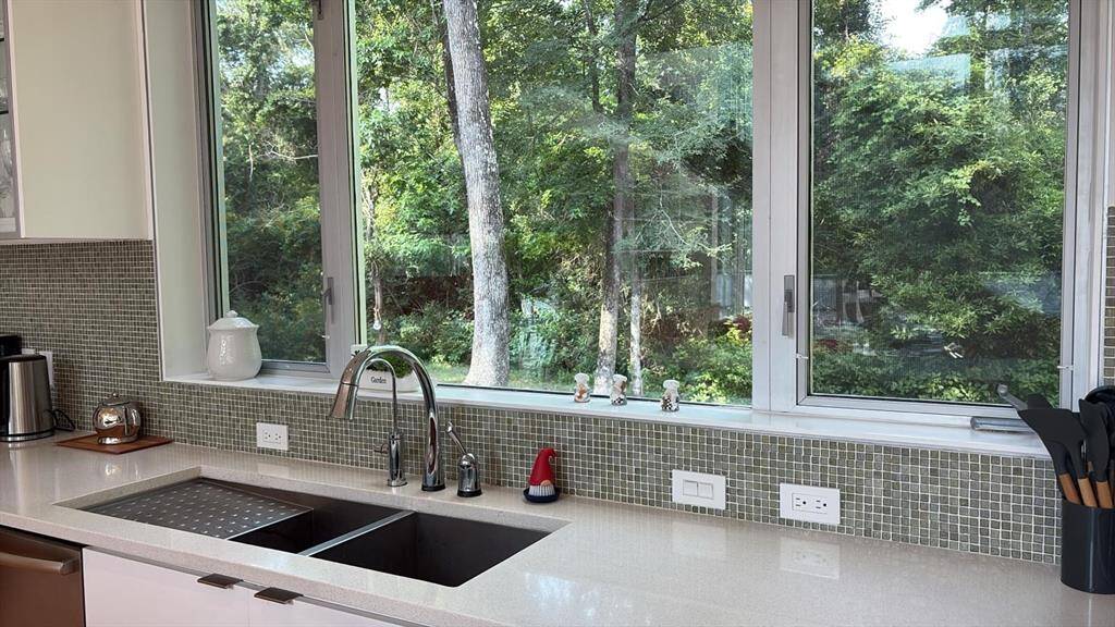 Enjoy peaceful wooded views through oversized kitchen windows, complemented by quartz counters and modern finishes.