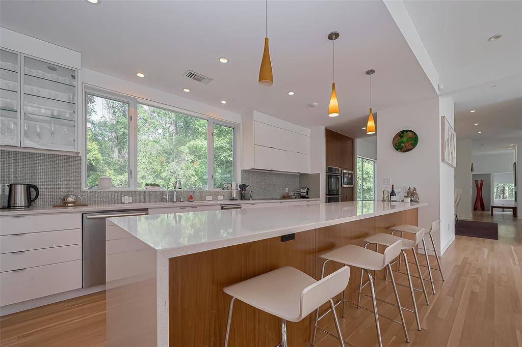 Massive quartz island with seating and pendant lighting anchors the kitchen’s contemporary design.