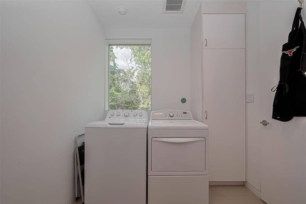 Dedicated laundry space with natural light, built-in storage, and full-size washer and dryer.