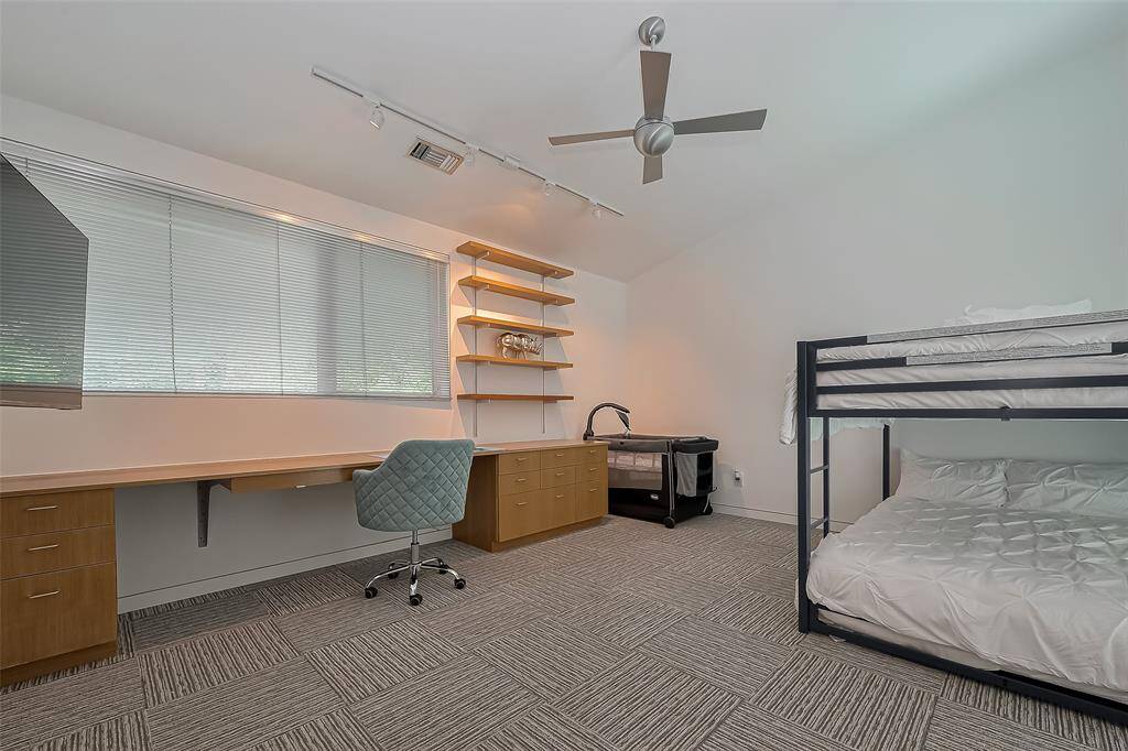 Spacious bunk room doubles as a home office with custom desk, shelving, and built-in storage.