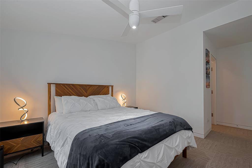 Modern bedroom with unique lighting, fan, and walk-in access to ensuite bath.