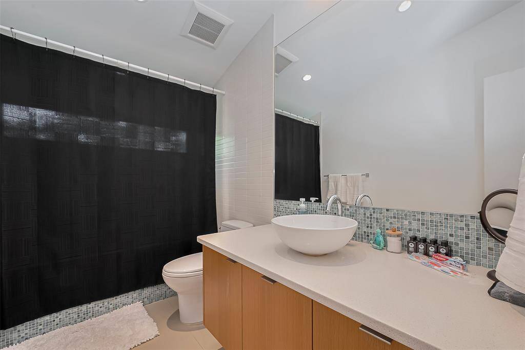 Modern guest bath with bowl sink, mosaic backsplash, and sleek cabinetry.