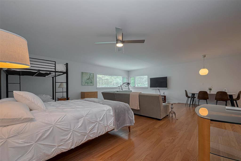 Spacious open-concept suite featuring a queen bed, bunk beds, and a modern ceiling fan for comfort.