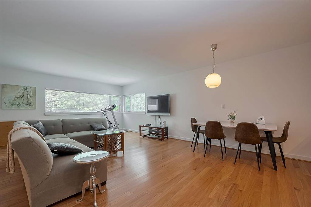 Bright living space with flat-screen TV, natural light, and a stylish dining nook.