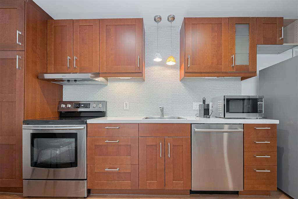 Fully equipped kitchen with rich wood cabinetry, stainless steel appliances, and tile backsplash.