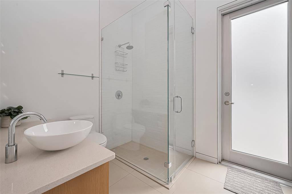 Sleek bathroom with frameless glass shower, vessel sink, and direct access to outdoor space.