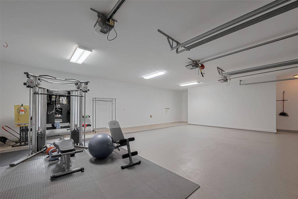 Oversized garage features epoxy flooring and a versatile home gym setup.