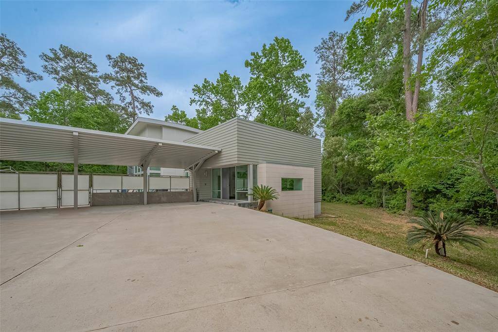 Sleek modern exterior with metal siding, large driveway, and covered carport.