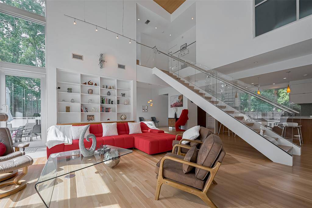 Soaring ceilings, a statement red sectional, and custom built-ins define this light-filled, open-concept living area.