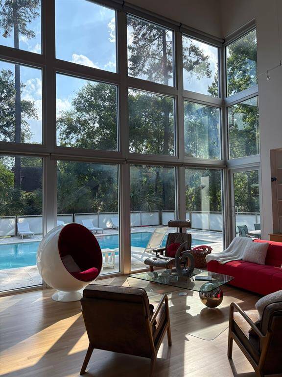 Floor-to-ceiling windows fill the living space with natural light and offer stunning views of the pool and lush surroundings.