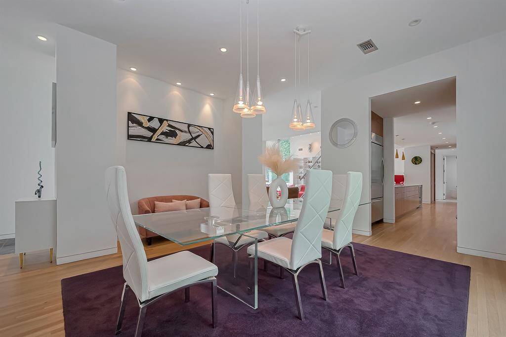 Elegant formal dining room featuring a glass table, designer lighting, and a rich purple rug that adds a touch of sophistication.