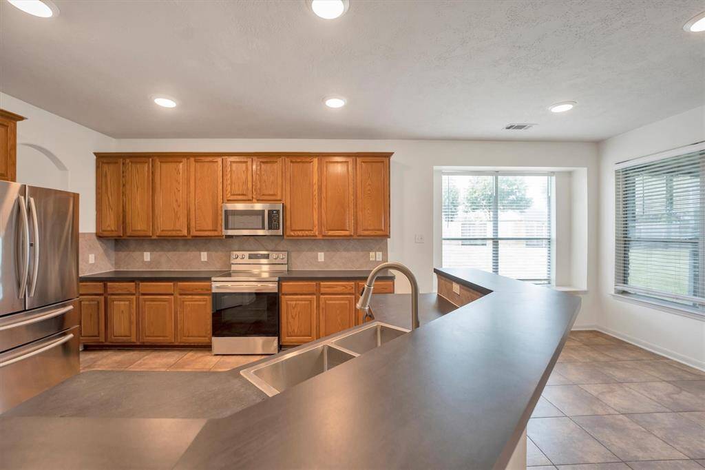 Discover the expansive kitchen featuring a new sink, stainless steel appliances, and generous counters and cabinetry.