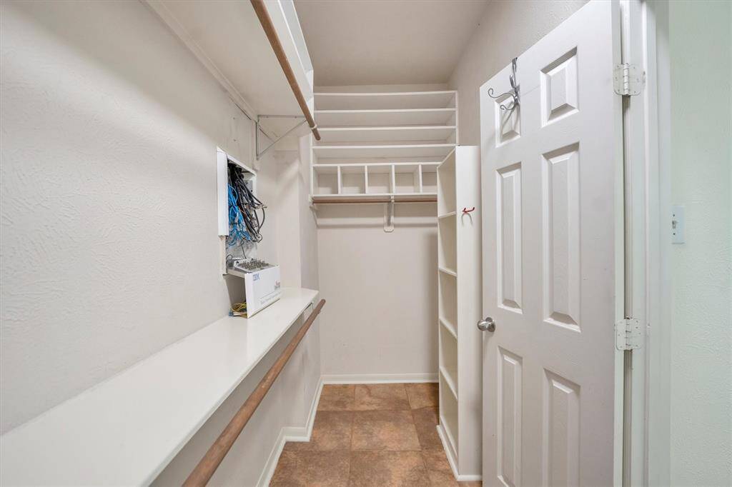 Spacious walk-in closet with built-in shelves for organized clothing and shoe storage.