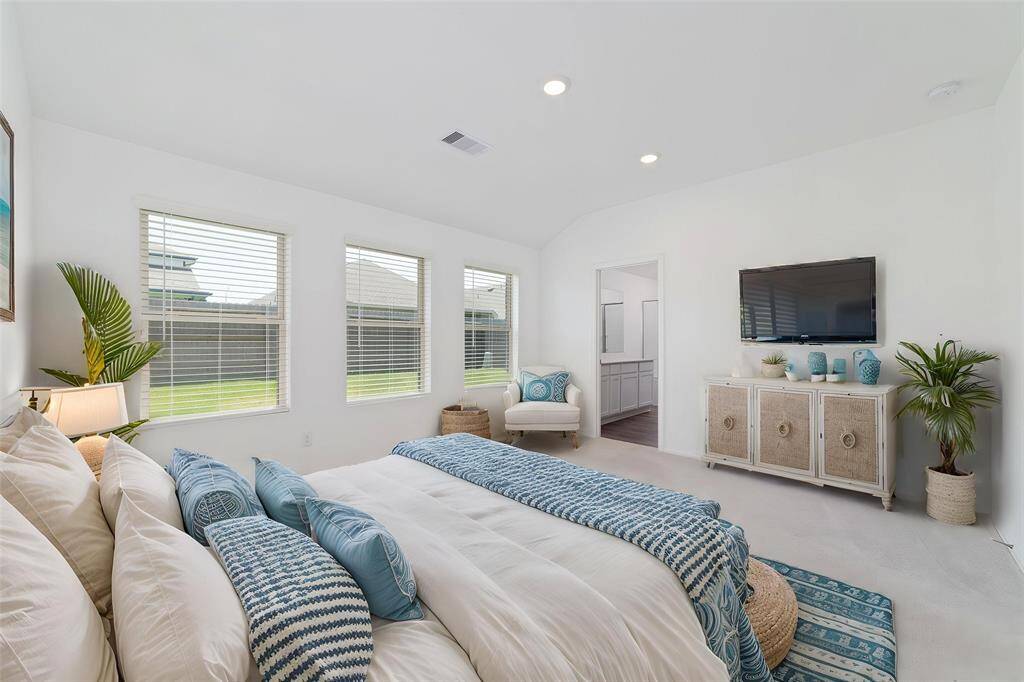 Primary bedroom flooded with natural light, overlooking the backyard.