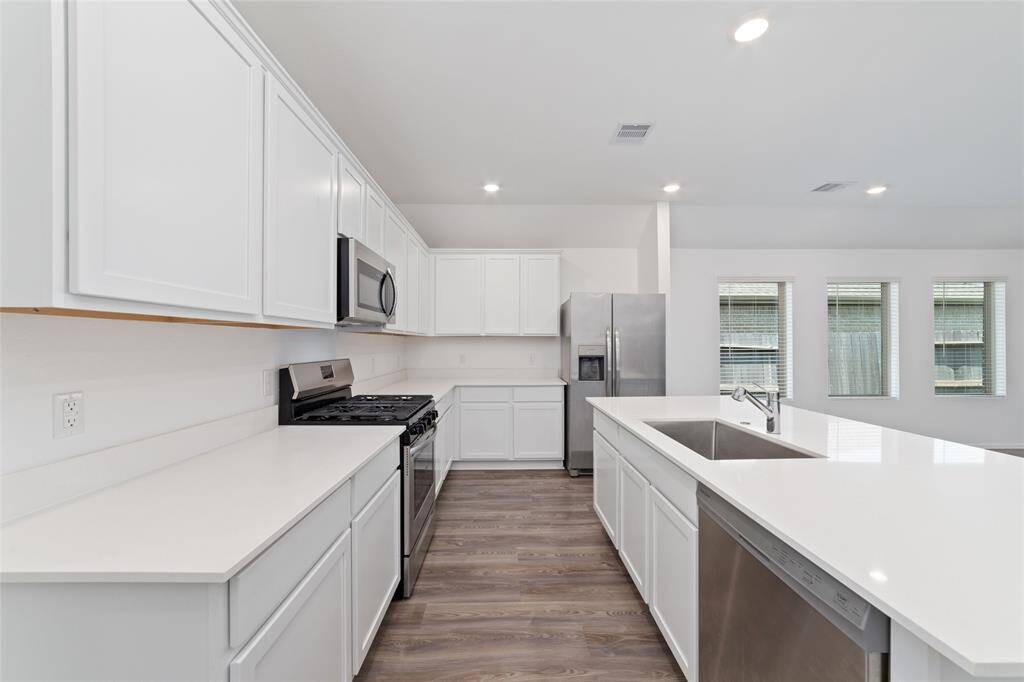 Giant island kitchen with quartz counters, ample counter space, and tons of cabinets.