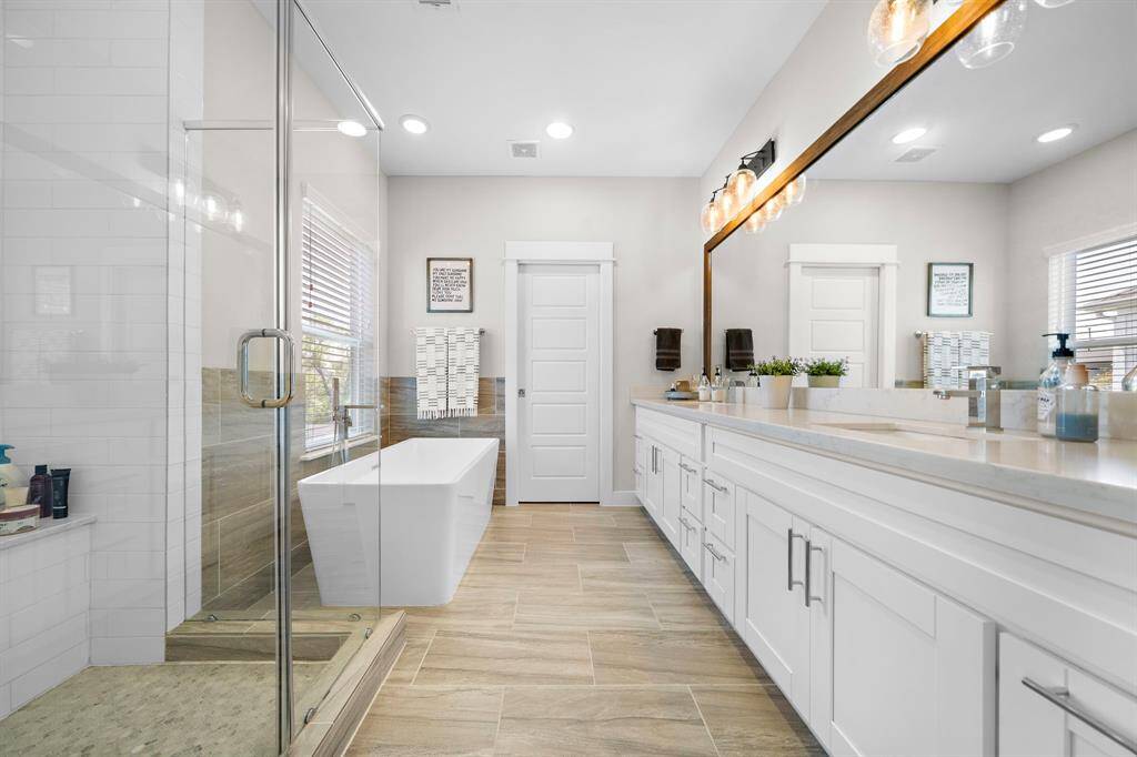 Sleek primary bathroom featuring double sinks, walk in-shower, soaking tub and private water closet.