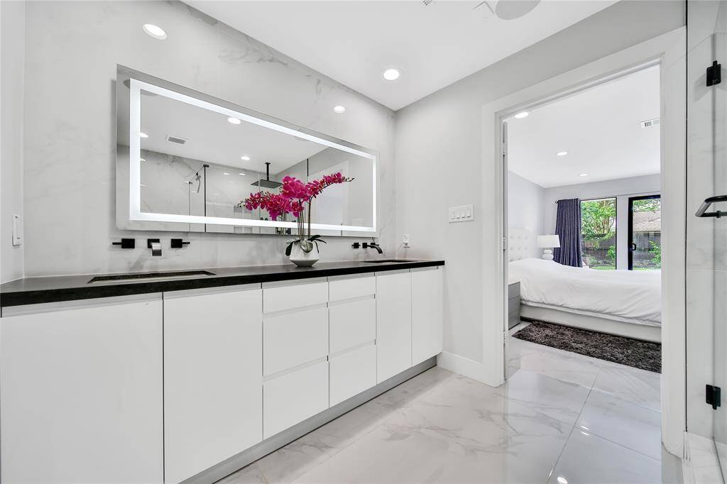 Stunning primary bathroom with glass shower, double sinks, and spacious walk-in closet.