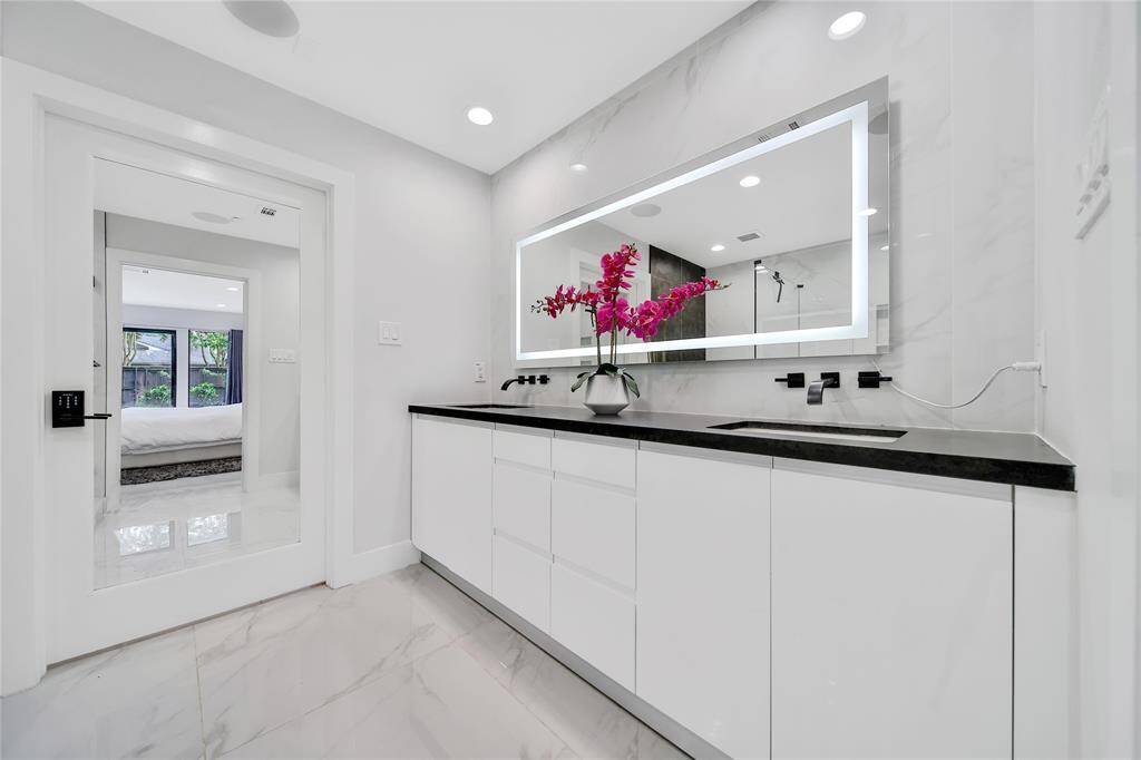 Stunning primary bathroom with glass shower, double sinks, and spacious walk-in closet.