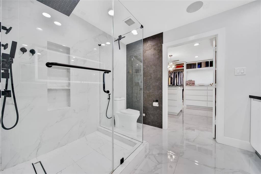 Stunning primary bathroom with glass shower, double sinks, and spacious walk-in closet.