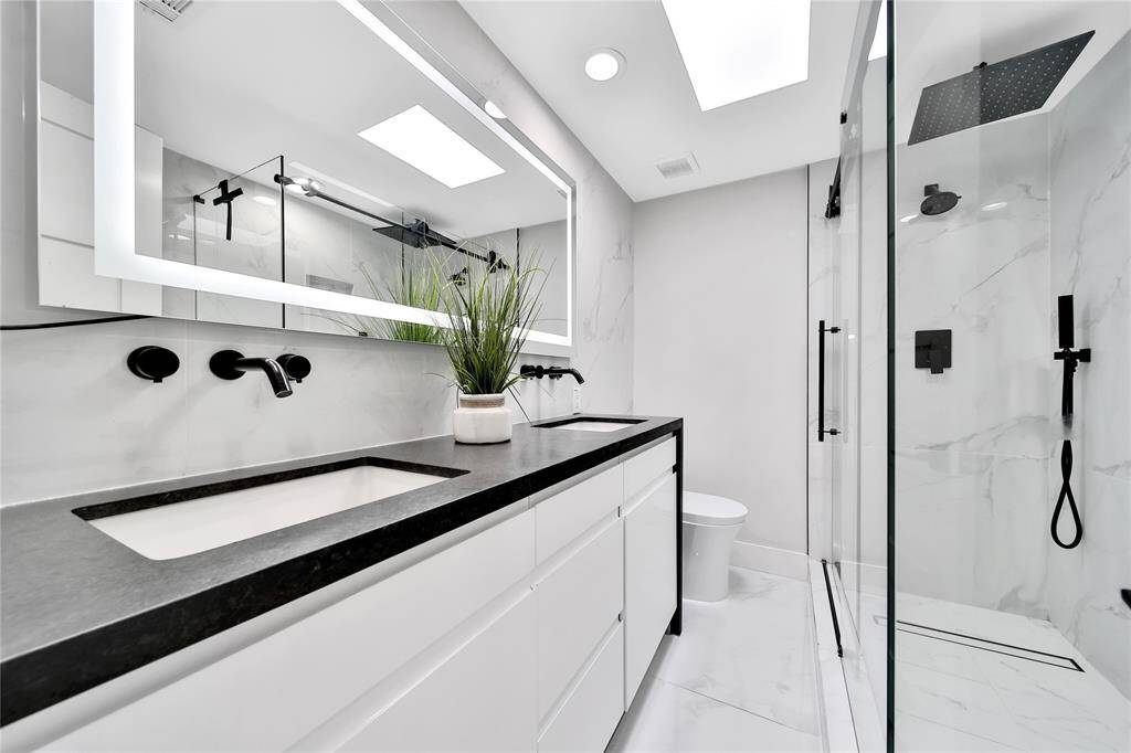 Upstairs secondary bathroom features glass shower and dual sinks.