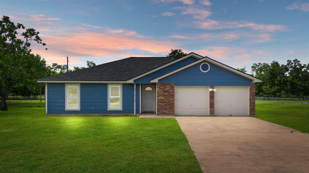 Charming home with a spacious front lawn, beautifully highlighted by a vibrant sunset.