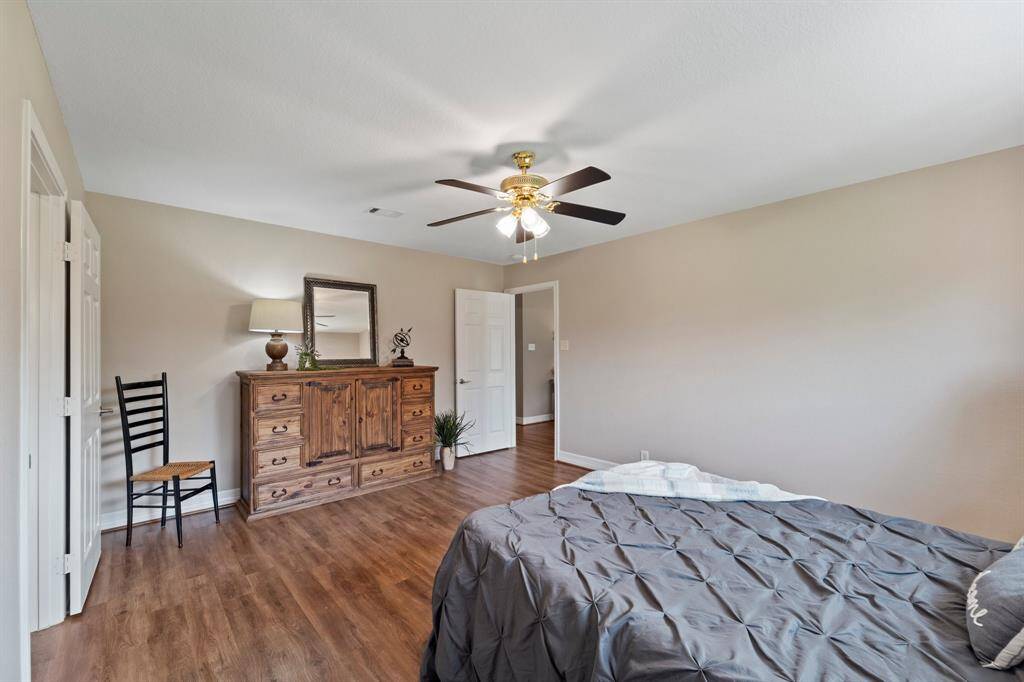 A bright bedroom featuring wood flooring and a large window that invites natural light, perfect for relaxation.