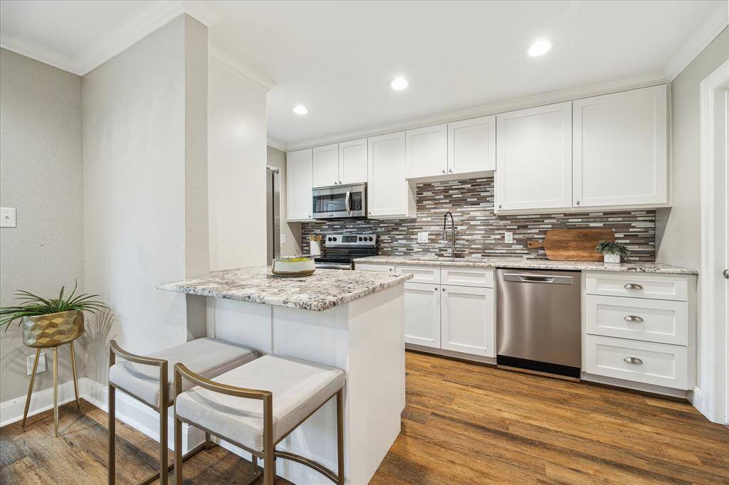Crisp white cabinetry, stainless appliances, and a granite-topped peninsula create a stylish and functional heart of the home.