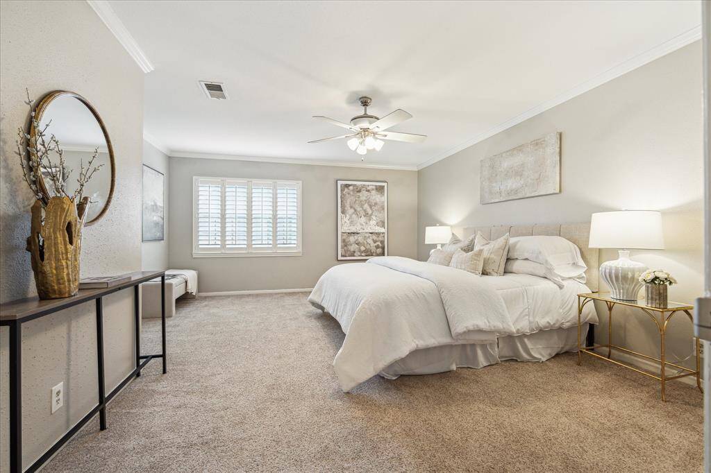 Now upstairs, discover the spacious and serene primary bedroom featuring plush carpet, elegant crown molding, and timeless plantation shutters for soft, natural light.